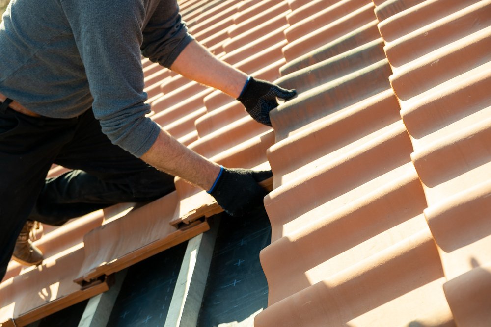 Person replacing tiles on a roof